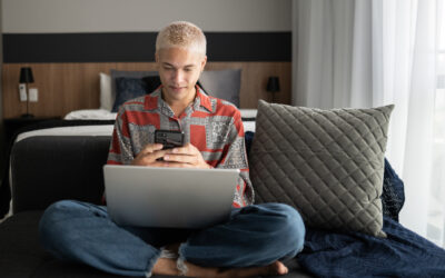 Gen Z young man using phone and laptop at home